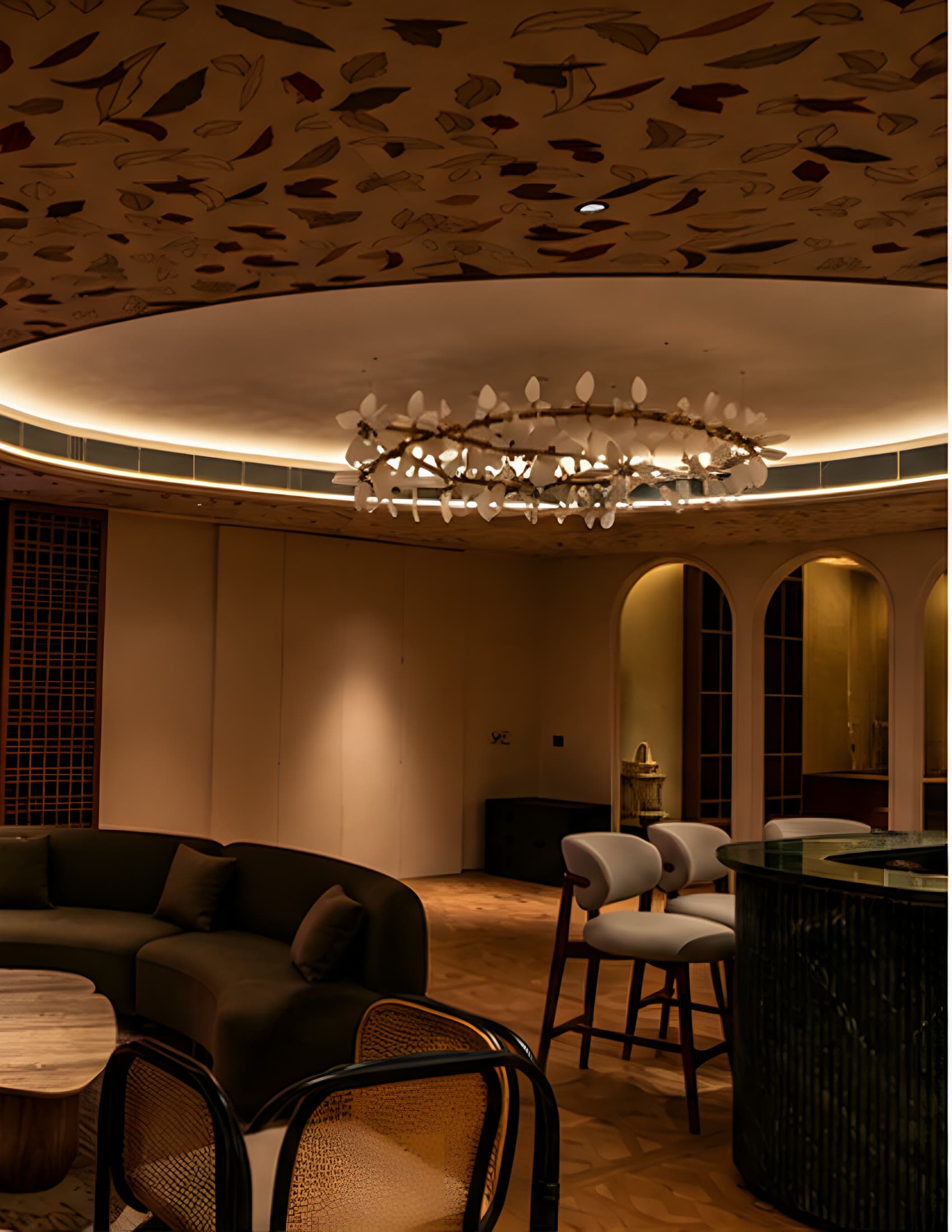 The studio lounge under its oval cove ceiling: a leaf chandelier above curved sofas, a bar with high stools and lit arched alcoves beyond.